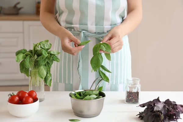 Woman with fresh basil in kitchen — Stock Photo, Image