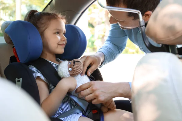 Father buckling his little daughter in car safety seat — Stock Photo, Image