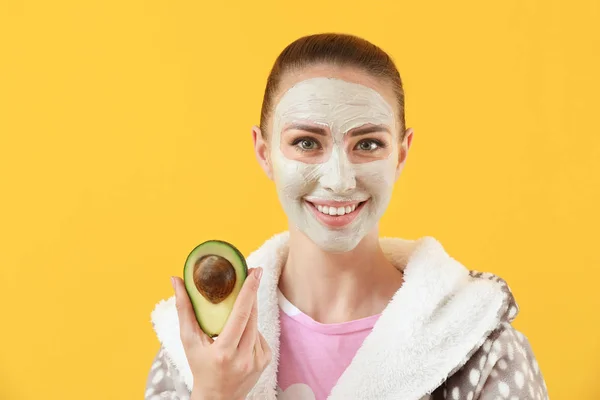 Beautiful young woman with facial mask and avocado on color background — Stock Photo, Image