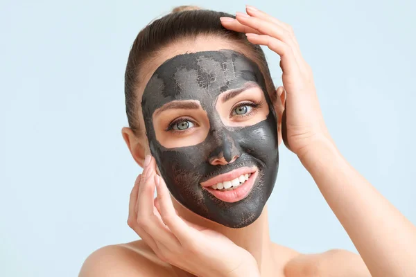 Beautiful young woman with facial mask on color background — Stock Photo, Image