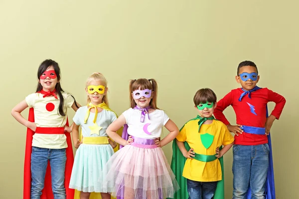 Lindos niños pequeños vestidos como superhéroes en el fondo de color — Foto de Stock