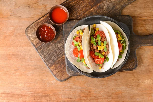Pfanne mit leckeren Tacos auf Holztisch — Stockfoto