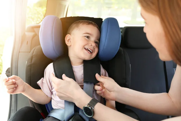 Moeder knik haar kleine zoon in de autostoel — Stockfoto