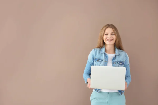 Schöne junge Frau mit Laptop auf farbigem Hintergrund — Stockfoto