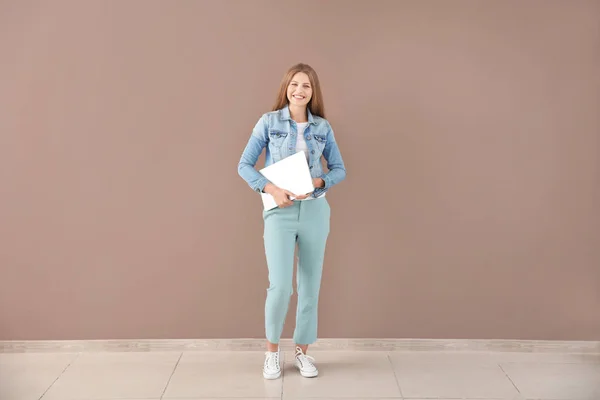 Hermosa mujer joven con ordenador portátil contra la pared de color — Foto de Stock