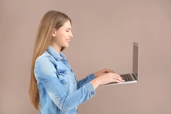 Mooie jonge vrouw werkt aan de voorgestelde laptop tegen kleur achtergrond — Stockfoto