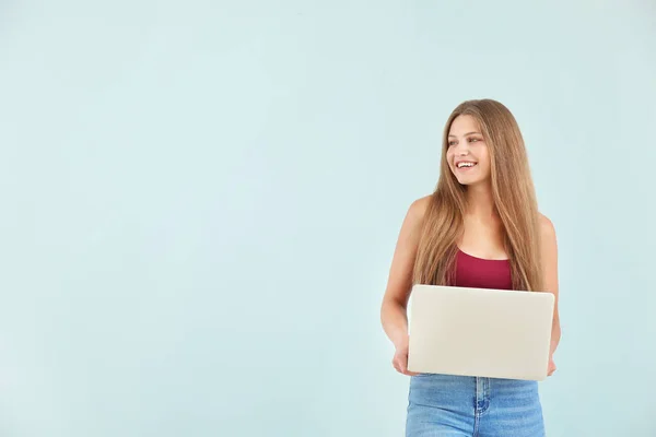 Schöne junge Frau mit Laptop auf farbigem Hintergrund — Stockfoto