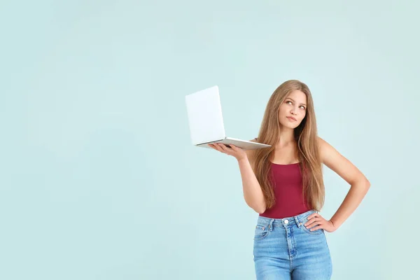 Thoughtful young woman with laptop on color background — Stock Photo, Image