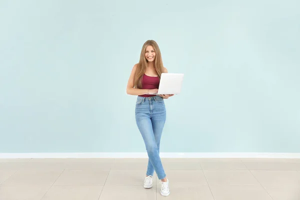 Schöne junge Frau mit Laptop gegen Farbwand — Stockfoto