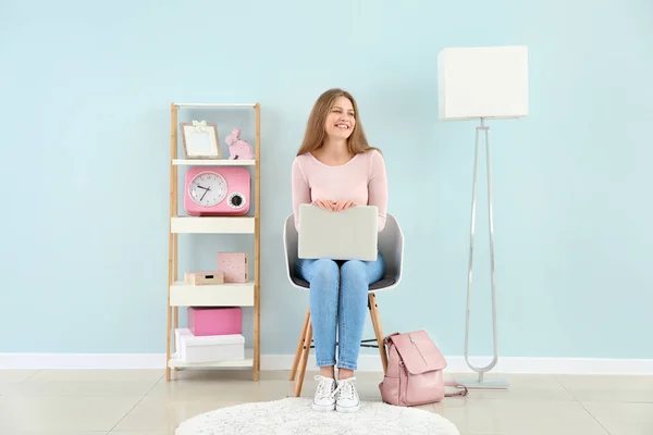 Mooie jonge vrouw met laptop zittend op de stoel thuis — Stockfoto