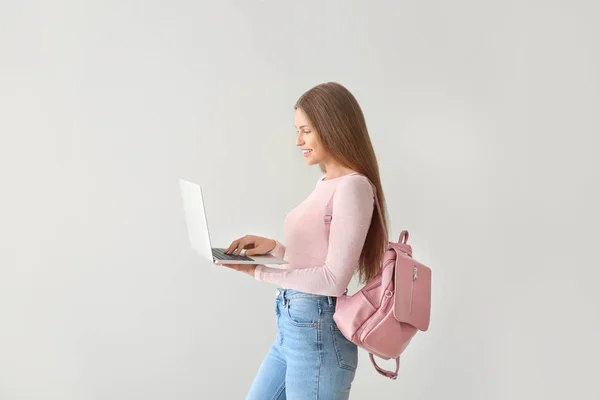 Female student with laptop on light background — Stock Photo, Image