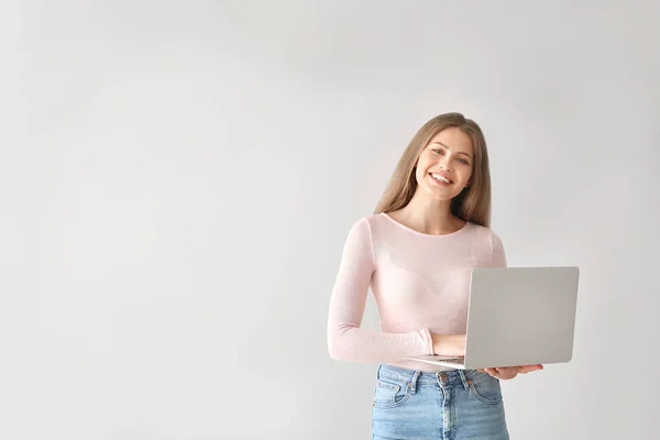 Schöne junge Frau mit Laptop auf hellem Hintergrund — Stockfoto