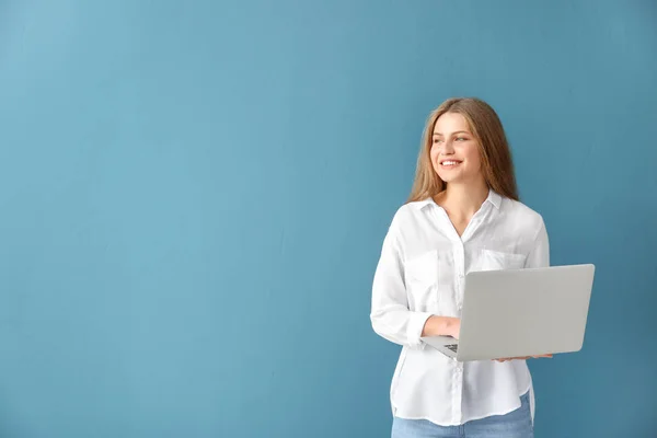 Schöne junge Frau mit Laptop auf farbigem Hintergrund — Stockfoto