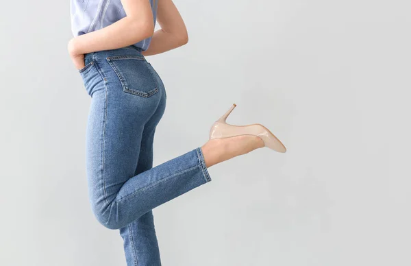 Mujer joven con pantalones vaqueros elegantes sobre fondo claro — Foto de Stock