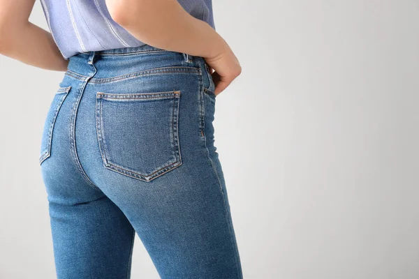 Giovane donna che indossa pantaloni jeans alla moda su sfondo chiaro — Foto Stock