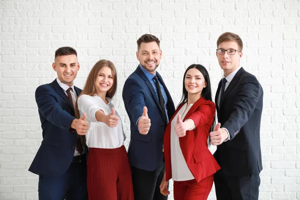 Team van zakenmensen tonen thumb-up gebaar in de buurt van witte bakstenen muur — Stockfoto