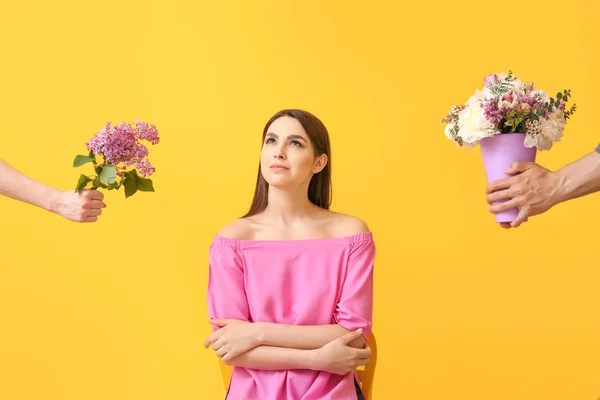 Thoughtful young woman choosing flowers on color background — Stock Photo, Image