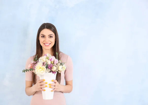 Красива молода жінка з букетом квітів на кольоровому фоні — стокове фото