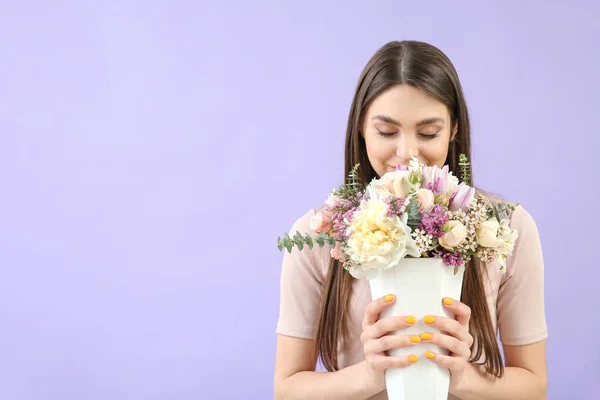 Vacker ung kvinna med bukett blommor på färgbakgrund — Stockfoto