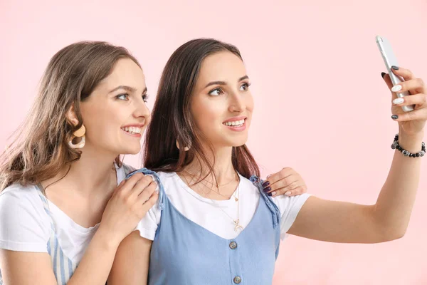 Portrait of happy lesbian couple taking selfie on color background — Stock Photo, Image