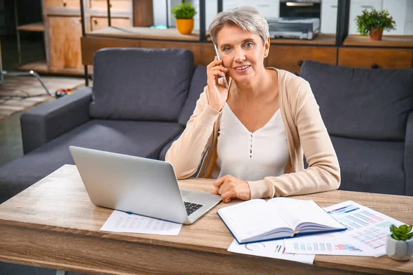 Mature businesswoman talking by phone in office — Stock Photo, Image
