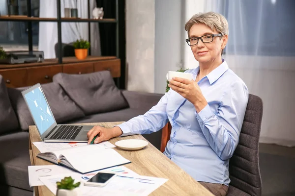 Mature businesswoman drinking coffee in office — Stock Photo, Image