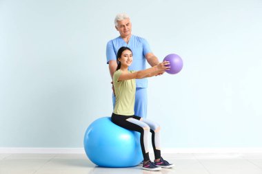 Klinikte Genç Asyalı kadınla çalışan olgun fizyoterapist
