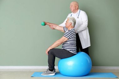 Klinikte olgun adam ile çalışan kıdemli fizyoterapist