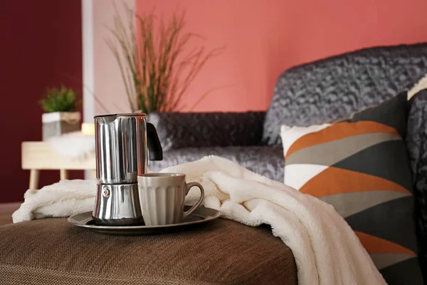 Coffee pot with cup on soft pouf in living room — Stock Photo, Image