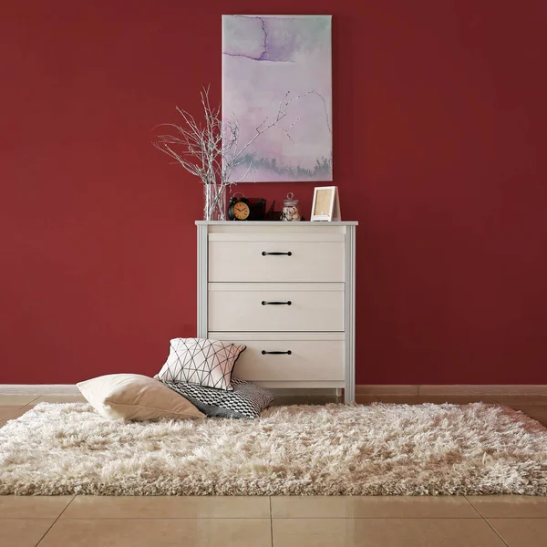 Chest of drawers with stylish decor and pillows near color wall in room — Stock Photo, Image