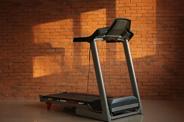 Modern treadmill near brick wall — Stock Photo, Image