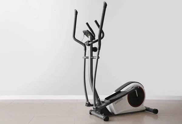 Modern exercise machine near light wall — Stock Photo, Image