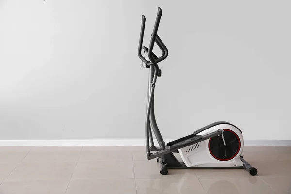 Modern exercise machine near light wall — Stock Photo, Image