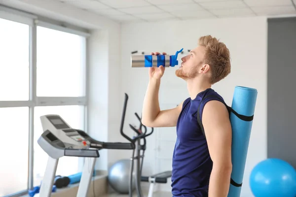 Sporty young man drinking water in gym — Stock Photo, Image