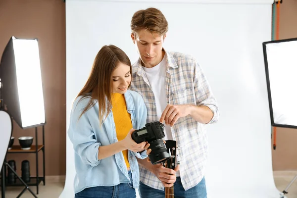 Fotógrafo profesional mostrando fotos a modelo en estudio —  Fotos de Stock