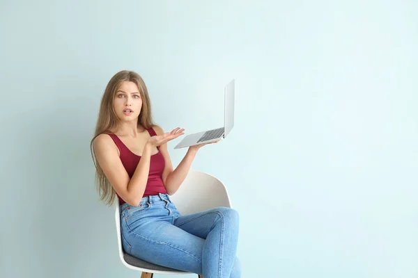 놀란 젊은 여자와 노트북 색상 배경에 대 한 의자에 앉아 — 스톡 사진