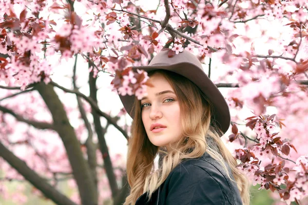 Mooie jonge vrouw in de buurt van bloeiende boom op de lente — Stockfoto