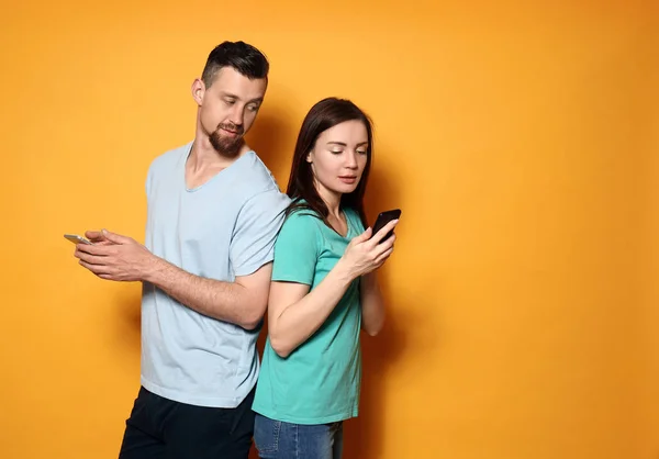 Young couple with mobile phones on color background — Stock Photo, Image