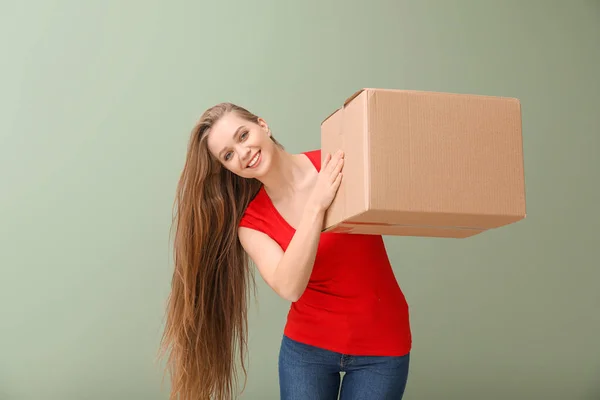 Young woman with cardboard box on color background — Stock Photo, Image