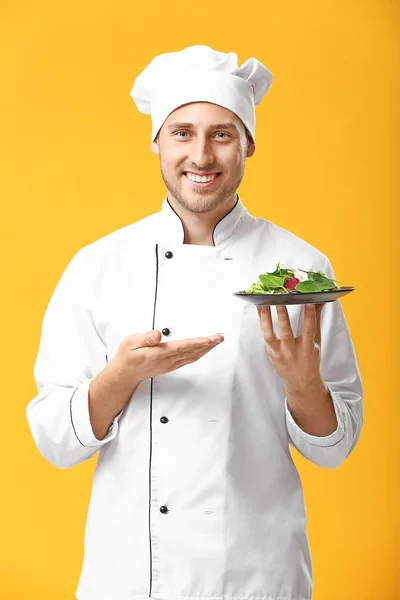 Pohledný mužský kuchař se salátem na barevném pozadí — Stock fotografie