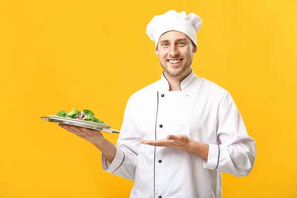 Bonito chef masculino com salada sobre fundo de cor — Fotografia de Stock