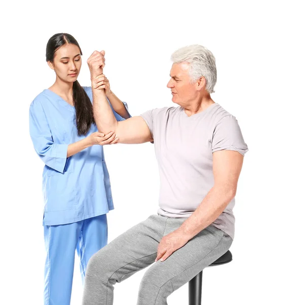 Молодой азиатский физиотерапевт, работающий со зрелым мужчиной на белом фоне — стоковое фото
