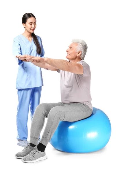 Young Asian physiotherapist working with mature man on white background — Stock Photo, Image