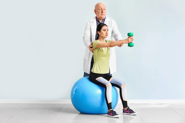 Senior physiotherapist working with young Asian woman in clinic — Stock Photo, Image