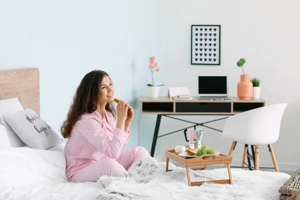 Beautiful young woman having breakfast in bed — Stock Photo, Image