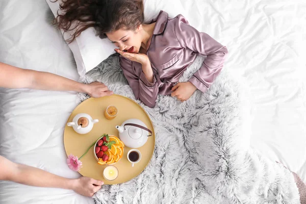 Young woman receiving breakfast in bed from her beloved husband — Stock Photo, Image