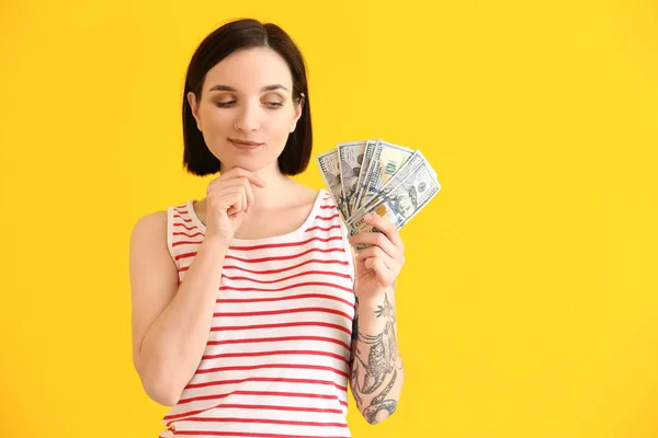 Thoughtful young woman with dollar banknotes on color background — Stock Photo, Image