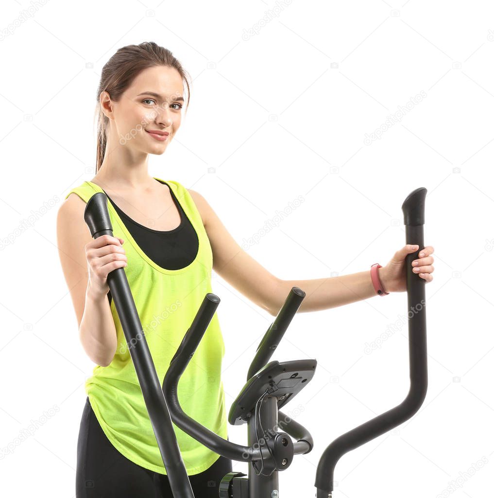 Sporty young woman training on machine against white background