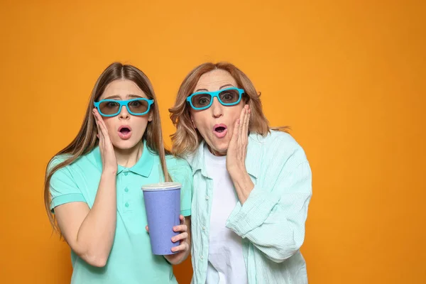 Madre emotiva con sua figlia a guardare film su sfondo a colori — Foto Stock