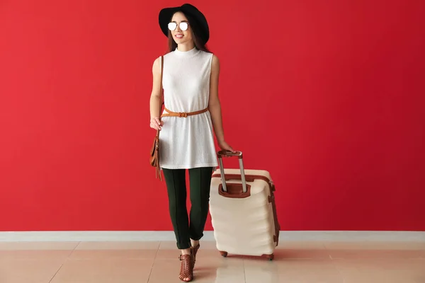 Going young woman with suitcase near color wall — Stock fotografie